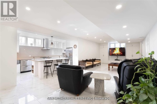 Modern open-concept basement living area with kitchen island and fireplace on TV - 1138 Garden Road Mississauga