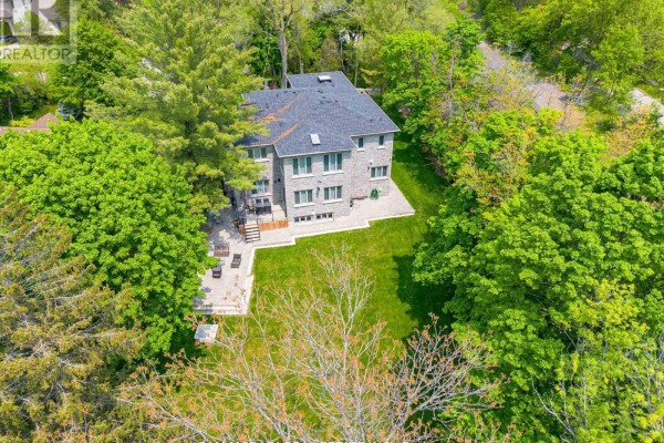 Stone house with patio and large backyard surrounded by trees - 1138 Garden Road Mississauga
