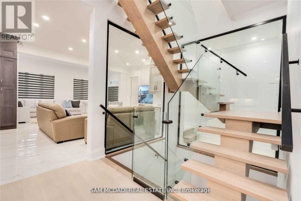 Floating wood staircase with glass railings and living area view - 1138 Garden Road Mississauga