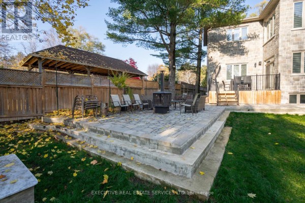White kitchen with stainless steel appliances, quartz countertops, and a central island with stools. - 1138 Garden Road, Mississauga