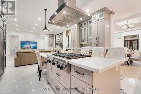 Modern kitchen with island stovetop & range hood, open to living room with TV - 1138 Garden Road Mississauga