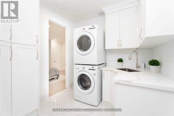 Stacked washer/dryer, sink, & white cabinetry in laundry room - 1138 Garden Road Mississauga