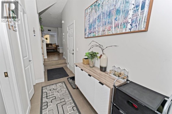 Entrance hallway with light grey walls, tiled floor, and a large abstract painting above a console table. - 114, 300 Marina Drive, Chestermere