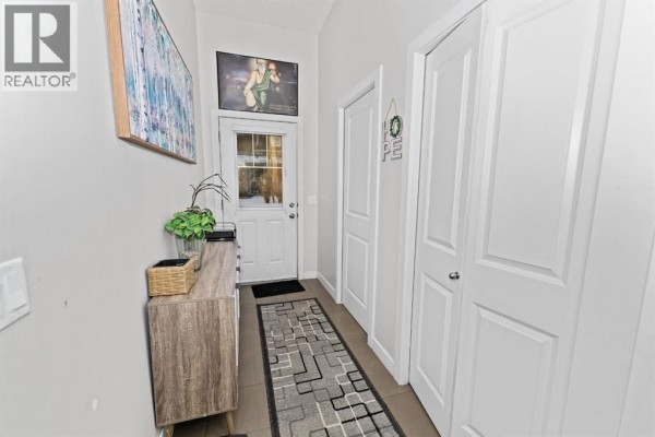 Hallway leading to a back door with a white door, two storage closets, and a runner rug. - 114, 300 Marina Drive, Chestermere