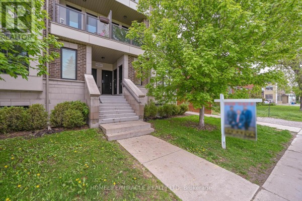 Front exterior of townhouse complex with lawn and sidewalk. - 114 - 256 Royal York Road, Toronto
