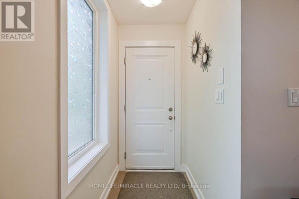 Interior view of a townhouse entryway with a white door and window. - 114 - 256 Royal York Road, Toronto
