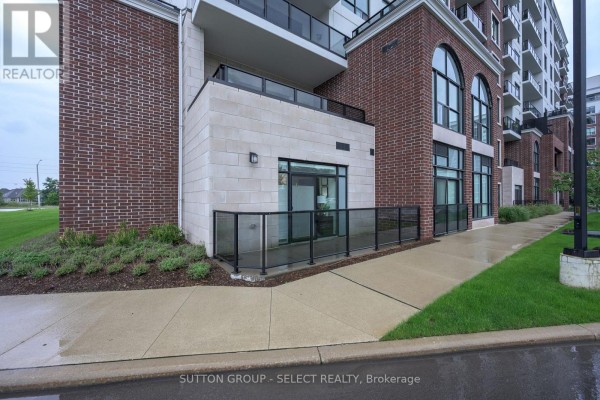 Ground level view of building entrance with brick and stone exterior, glass railing, and walkway. - 114 - 480 Callaway Road, London North