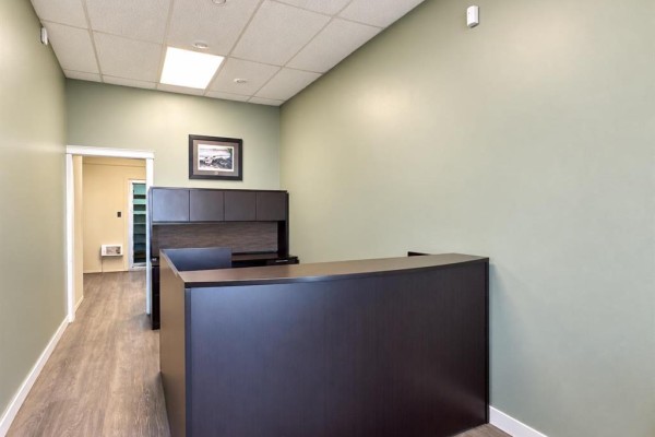 Close-up view of the reception desk and office hallway entrance, with light green walls. - 114 5th Avenue N, Swan River