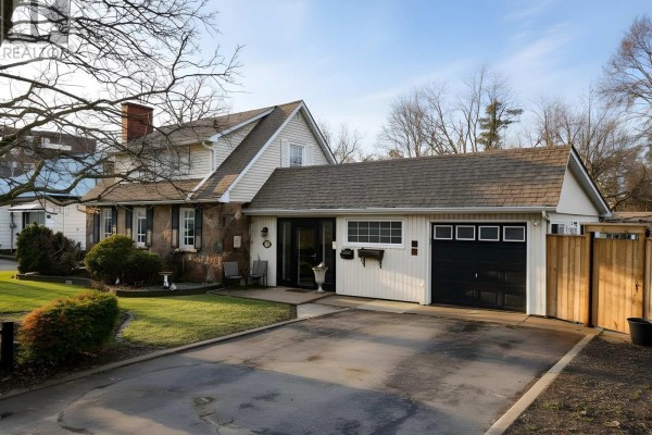 A wider angle of the house, showcasing the driveway, garage, and side yard. - 114 Colborne Street W, Kawartha Lakes