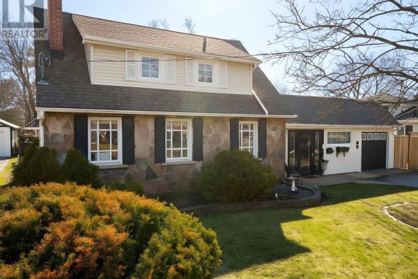 Front lawn view of the house with lush green grass and mature evergreen shrubs. - 114 Colborne Street W, Kawartha Lakes
