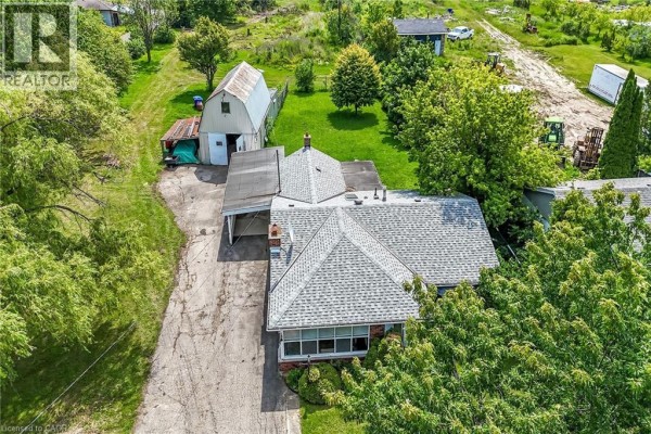 Aerial view of a bungalow with a large detached barn and surrounding trees. - 114 Second Road E, Stoney Creek