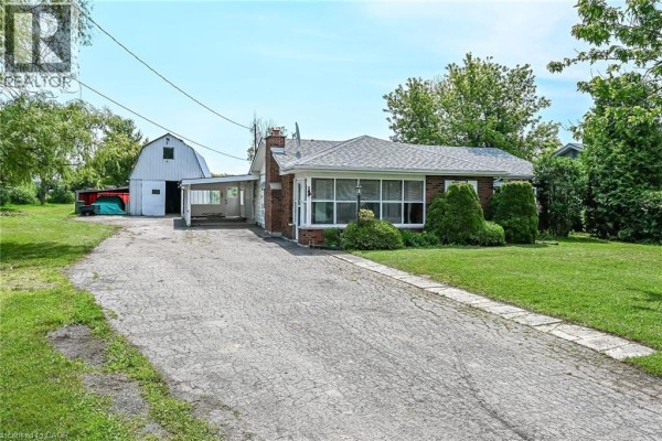 Side angle of the bungalow, showing the driveway, carport, and front entrance. - 114 Second Road E, Stoney Creek