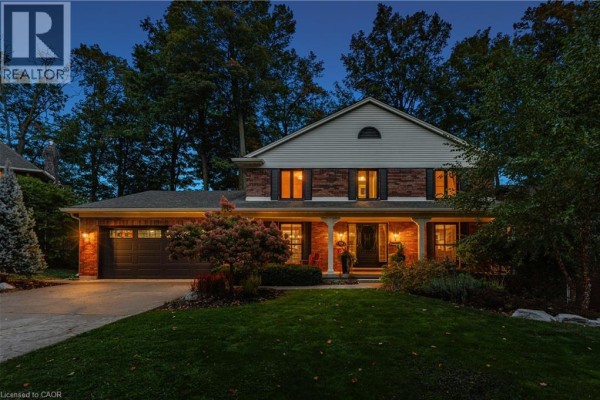 Brick house exterior at dusk with illuminated windows and porch lights. - 114 Frederick Banting Place, Waterloo