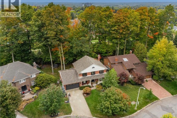 Aerial view of a two-story brick house with an attached garage and trees. - 114 Frederick Banting Place, Waterloo