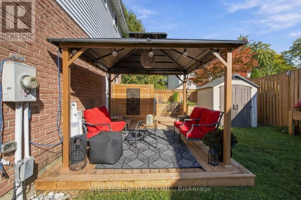 Backyard deck with a gazebo, red outdoor seating, and two sheds. - 114 Hearthside Place, London East