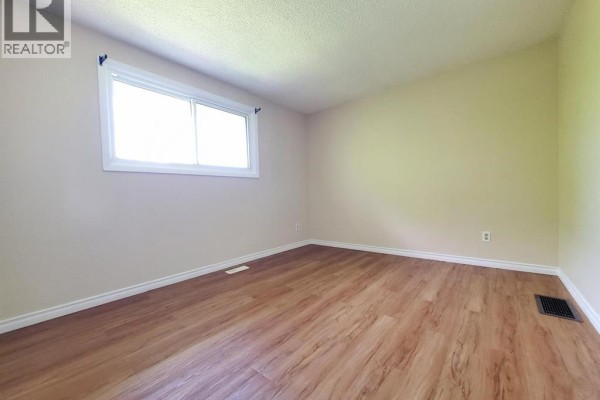 Empty bedroom with light beige walls, wood-look laminate flooring, and a single window. - 114 Lillian Drive Unit# B, Waterloo