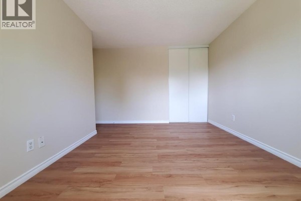 Empty bedroom with beige walls, wood-look laminate flooring, and bi-fold closet doors. - 114 Lillian Drive Unit# B, Waterloo