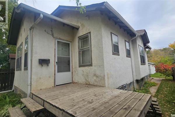 Side view of the house with a wooden deck and steps leading to the front door. - 114 N Avenue S, Saskatoon