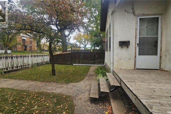 View of the yard from the front porch with a pathway and scattered fallen leaves. - 114 N Avenue S, Saskatoon