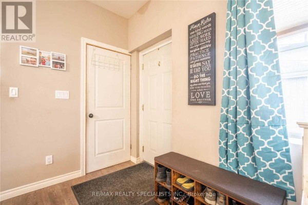 Interior hallway with two white doors, a shoe rack bench, and neutral-colored walls. - 114 Pearl Street, Brantford