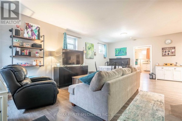Living room with a sofa, recliner, television, and a dining table with chairs. - 114 Pearl Street, Brantford