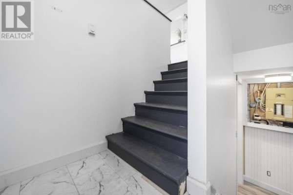 Dark gray painted stairs ascend a white wall, with tiled flooring and a utility area visible. - 114 Romkey Drive, Eastern Passage