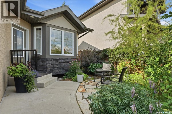 Pathway leading to front door with chairs and table in a garden setting. - 114 Senick Crescent, Saskatoon