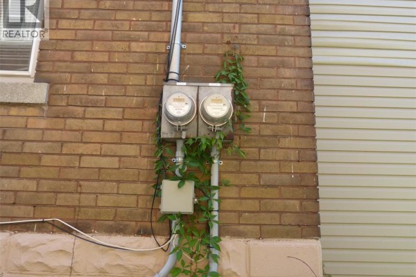 Close-up of two electrical meters mounted on a brick wall, partially covered by ivy. - 1140 Giles Boulevard East, Windsor