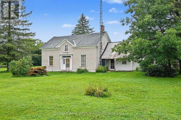 Side view of the farmhouse showing the attached single-story structure and surrounding trees. - 11422 7th Line Road, Elizabethtown Kitley