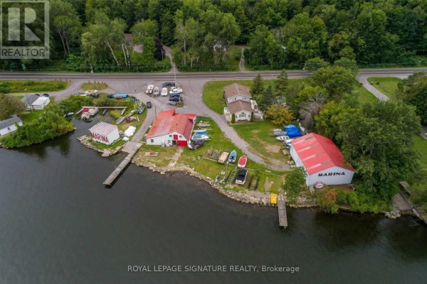 Overhead view of marina buildings, boats, docks, and a house adjacent to a road and lake. - 11438c Loyalist Parkway, Prince Edward County