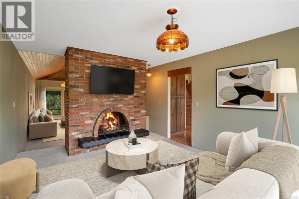 Living room with a large brick fireplace, television, coffee table, and sofa. - 1144 May St, Victoria