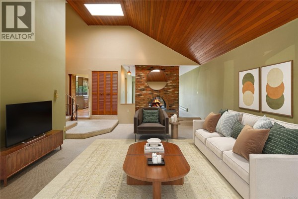 Living room with vaulted wood ceiling, brick fireplace, sofa, and armchair. - 1144 May St, Victoria
