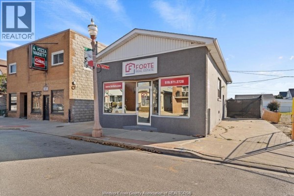 Street view of commercial building with adjacent brick building and parking area. - 1145 Erie Street East, Windsor