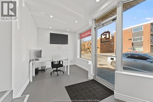 Interior view of commercial space showing office desk, computer, television, and entrance. - 1145 Erie Street East, Windsor