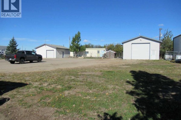 A grey pickup truck drives across an asphalt lot with several buildings. - 11450 89 Avenue, Grande Prairie