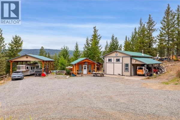 Outdoor buildings including a large workshop, carport, and a small shed with vehicles parked. - 11460 Hwy 97c Highway, Merritt