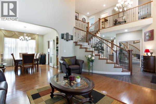 Living room with leather sofas, oval coffee table, and arched doorway to dining room. - 1149 Channelside Drive Sw, Airdrie