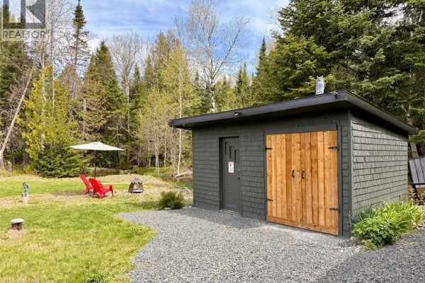 Dark brown wood-sided house with a covered front porch, wooden stairs, and a detached storage shed. - 11498 Route 17, Adams Gulch