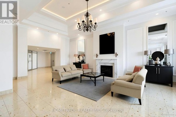 Lobby seating area with sofas, coffee table, fireplace, and chandelier. - 115 - 2 Maison Parc Court, Vaughan
