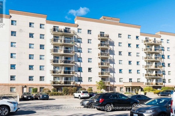 Front exterior of the apartment building with a parking lot in the foreground. - 115 - 736 Old Albert Street, Waterloo