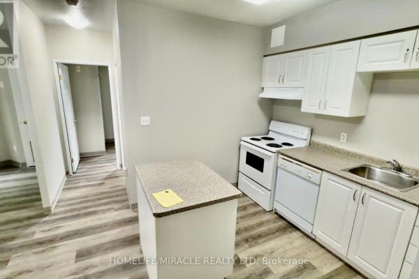Kitchen with white cabinets, light grey walls, and a small island. - 115 - 736 Old Albert Street, Waterloo