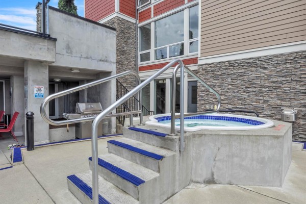 Elevated view of outdoor swimming pool and hot tub with surrounding concrete patio. - 115 2242 Whatcom Road, Abbotsford