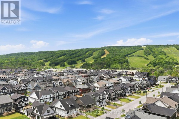 Aerial view of a suburban neighborhood with many houses and green hills in the background. - 115 Black Willow Crescent, Blue Mountains