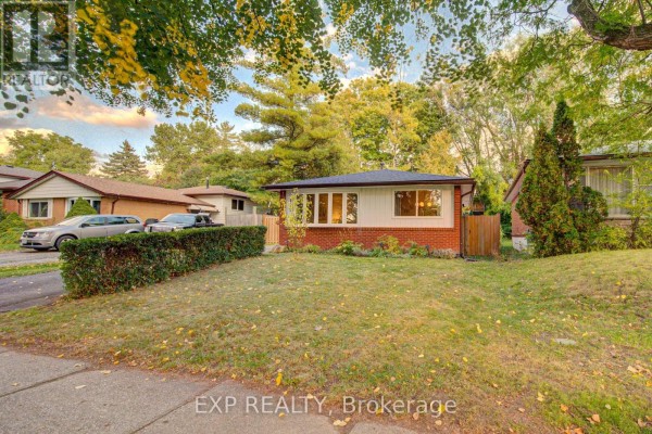 Side exterior of a brick and white house with a paved driveway and green lawn. - 115 Chopin Drive, Kitchener