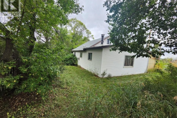 Exterior view of the house with white siding, green grass, and surrounding trees. - 115 Halyard Street, Pennant
