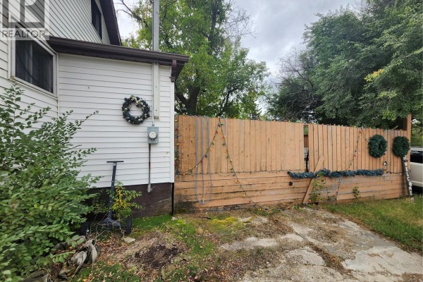 Side of the house with white siding, a meter, and a tall wooden fence with lights. - 115 Halyard Street, Pennant