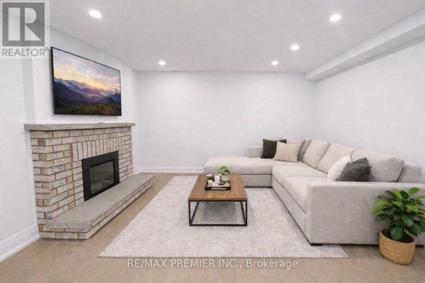 Living room featuring a sectional sofa, brick fireplace, and mounted television. - 115 Mapes Avenue, Vaughan