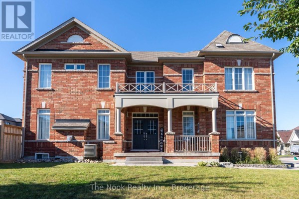 Front view of a large red brick house with a double door entrance and a balcony above the porch. - 115 Noden Crescent, Clarington