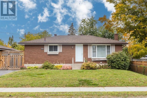 Front exterior of a red brick bungalow with a well-maintained lawn and garden beds. - 115 Victoria Avenue N, Kawartha Lakes