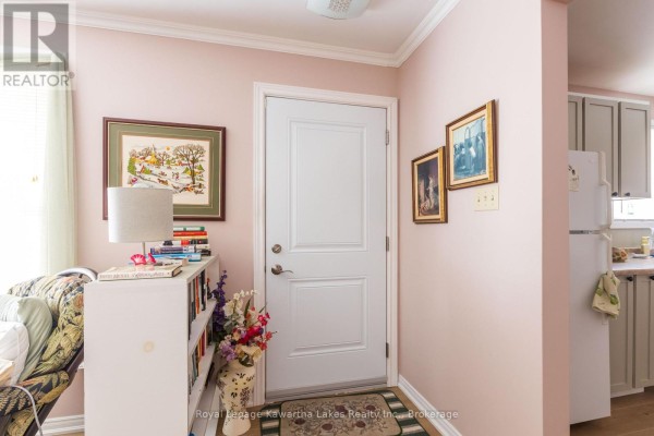Interior entryway with a white door, bookshelf, and light pink walls. - 115 Victoria Avenue N, Kawartha Lakes